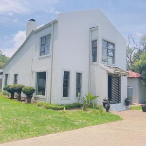 a white house with a grass yard in front of it at Cheerful 3-bedroom home with backup power around Sandton in Sandton