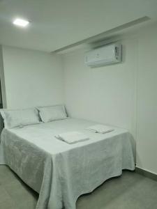a bed in a white room with two napkins on it at Excelente Flat beira-mar in Cabedelo