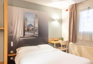 1 dormitorio con cama, escritorio y ventana en B&B HOTEL Limoges 2, en Limoges