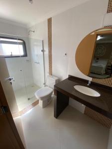 a bathroom with a toilet and a sink and a mirror at Grande Hotel in Paranavaí