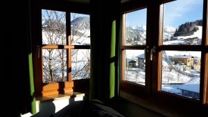 um quarto com três janelas com vista para uma montanha de neve em Apartments Embach em Embach