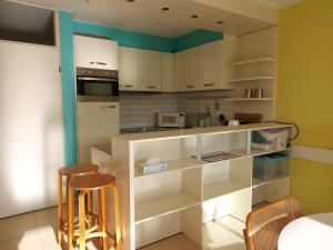 a kitchen with white cabinets and two bar stools at Studio Zeedijk Koksijde in Koksijde +2 photos