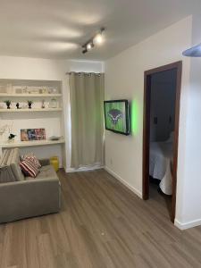 a living room with a couch and a television on a wall at Loft Residencial GreenPark by Staya in Brasilia