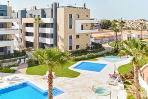 an apartment with two pools and palm trees and buildings at Apartament Flamenca Village Lime & Lemon in Orihuela Costa