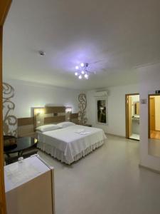 a large bedroom with a bed and a ceiling at Grande Hotel in Paranavaí