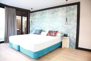a bedroom with a bed with a large wall at Hotel Suites Moma Centro in Villanueva de la Serena