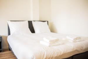 a white bed with towels stacked on top of it at The Hendrick in Rotterdam