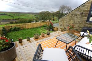 un patio con mesa y sillas en una terraza en Farways Den, en Haworth