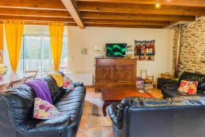 a living room with two leather couches and a television at Gite de charme, idéal pour 4 in Saint-Jory-de-Chaleix