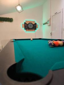 a pool table with a clock on the wall at Le Cosy'ppart - EasyLife in Bourgoin