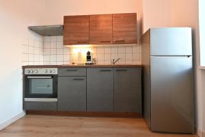 a kitchen with a stainless steel refrigerator and wooden cabinets at Gemütliches Stadtapartment im Zentrum von Ried im Innkreis in Ried im Innkreis