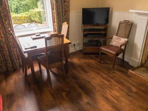 a living room with a dining table and a television at Glenterry Farmhouse in Kirkcudbright