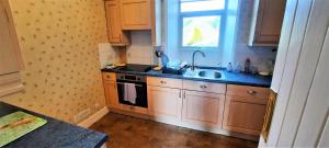 a kitchen with wooden cabinets and a sink and a window at Glenterry Farmhouse in Kirkcudbright