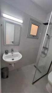 a white bathroom with a sink and a window at Elena Court Apartments in Ayia Napa
