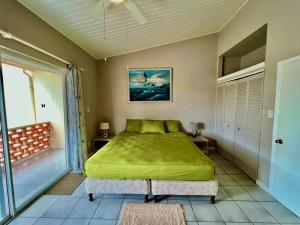 a bedroom with a green bed and a balcony at South Finger Villa in Jolly Harbour