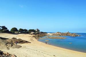 a beach with people on the sand and the water at Manoir de Kervegan : Le Logis du P’tit Levant in Lannion