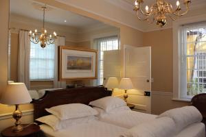1 Schlafzimmer mit 2 Betten, 2 Lampen und einem Kronleuchter in der Unterkunft Tintagel Guesthouse in Kapstadt