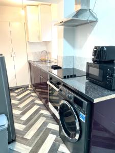 a kitchen with a washing machine and a microwave at Retro 3 bed, 2 En-suite Haven in Birmingham