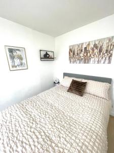 a white bedroom with a bed and two pictures on the wall at Retro 3 bed, 2 En-suite Haven in Birmingham