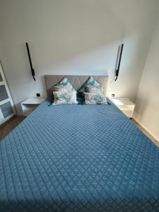 a bedroom with a blue bed with two pillows at Apartament Brzeźno Beach in Gdańsk