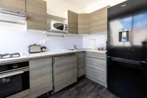 a kitchen with wooden cabinets and a black refrigerator at *L'Echappée* Balcon & Central in Chamalières