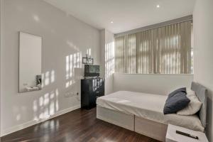 a white bedroom with a bed and a window at Chic 1 Bedroom Apartment in London