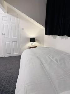 a bedroom with a large white bed and a lamp at Vinery Green Long Stay Offers in Knowsthorpe