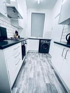 a kitchen with white cabinets and a washer and dryer at Vinery Green Long Stay Offers in Knowsthorpe