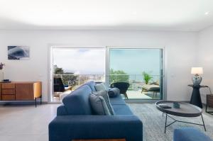 een woonkamer met een blauwe bank en een groot raam bij Panoramic Views - Terrace, Sea Views & Pool in Nazaré