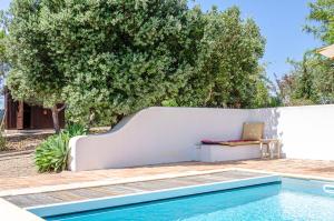 a pool with a bench next to a white wall at Casa Litoral in Melides