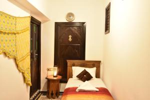 um pequeno quarto com uma cama e uma cabeceira em madeira em Dar Aya Fes em Fez