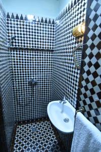 フェズにあるDar Aya Fesの白黒のタイル張りの壁、洗面台付きのバスルーム