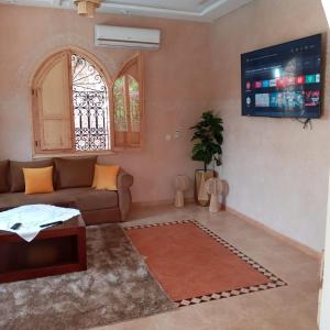 ein Wohnzimmer mit einem Sofa und einem TV in der Unterkunft Villa Korima in Marrakesch
