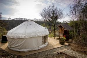 a large yurt on a wooden deck with a house at Ceridwen Glamping, double decker bus and Yurts in Llandysul