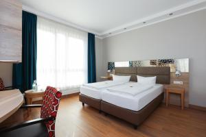 乌尔姆Hotel Blaubeurer Tor的一间卧室，有两张床、一张桌子和几把椅子