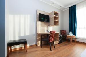 Zimmer mit einem Tisch, Stühlen und einem Schreibtisch in der Unterkunft Hotel Blaubeurer Tor in Ulm