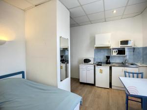 kuchnia z białymi urządzeniami i łóżko w pokoju w obiekcie Studio cosy proche des Thermes, centre-ville et nature, WiFi, animaux acceptés - FR-1-451-181 w mieście Lamalou-les-Bains