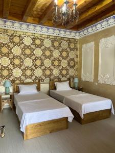 - une chambre avec deux lits et un mur revêtu de carrelage dans l'établissement Asia Central Boutique, à Boukhara