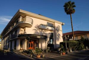 a white building with a palm tree in front of it at Hotel Bellavista in Marina di Varcaturo