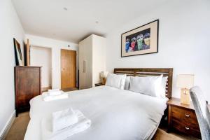 a bedroom with a large white bed and a chair at GuestReady - Lovely getaway in Highbury in London