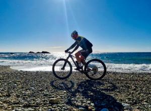 un hombre montando una bicicleta en la playa en Villa mit Whirlpool und phantastischer Aussicht en Capoliveri