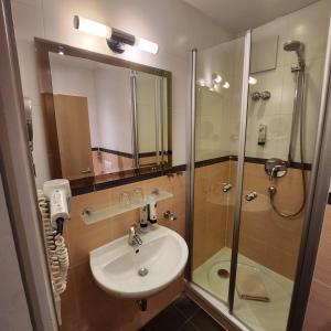 a bathroom with a sink and a shower with a glass door at Posthotel Traube in Donauwörth