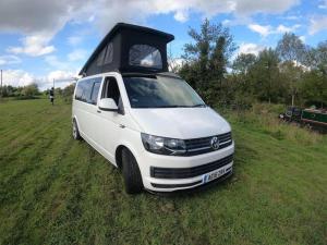 una furgoneta blanca estacionada en un campo con la puerta abierta en Stunning VW Camper Van, en Kirton