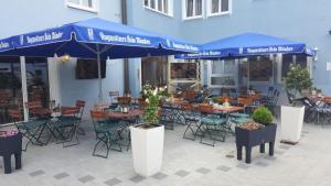 a patio with tables and chairs and blue umbrellas at Posthotel Traube in Donauwörth