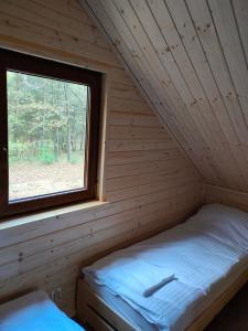 uma cama num quarto com uma janela em Domki Dygudaj 