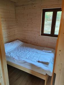 a bed in a wooden cabin with a window at Domki Dygudaj 
