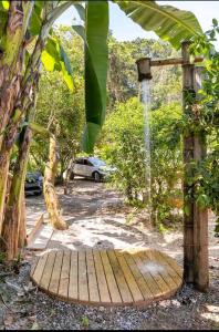 Prumirim Surf Suítes Hotel Ubatuba في أوباتوبا: رصيف خشبي به نافورة مياه في حديقة