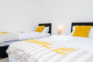 duas camas num quarto com amarelo e branco em 2 Bed Free Private Parking Leisure Contractor em Higham Ferrers