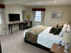 um quarto com uma cama, uma secretária e uma televisão em The Crown Hotel, Boroughbridge, North Yorkshire em Boroughbridge