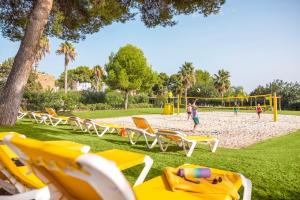 TUI MAGIC LIFE Cala Pada - All Inclusive في سانتا إيولاليا ديل ريو: حديقة بها كراسي وملعب كرة الطائرة